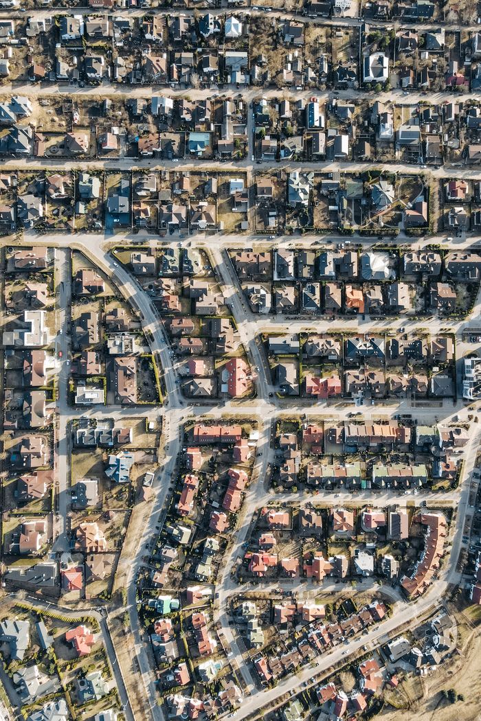 about-img-01 High-angle aerial view of a dense suburban neighborhood with organized streets and houses.